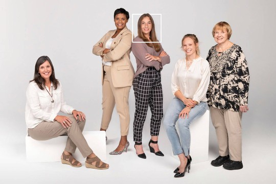 five women posing for a photo against a white backdrop.
