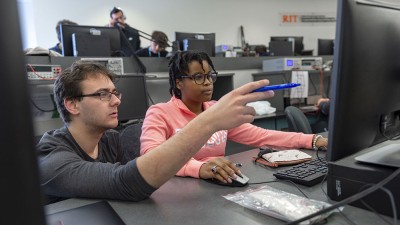 professor points to a student's computer in a lab.