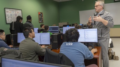 Professor teaching students who are sitting at computers.
