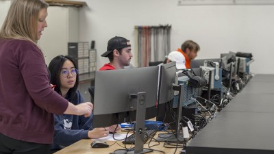 Professor teaching students who are sitting at computers.