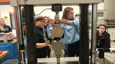 A group of students work with a large piece of lab equipment.