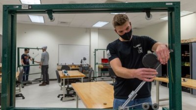 Student works on equipment with measuring tool.
