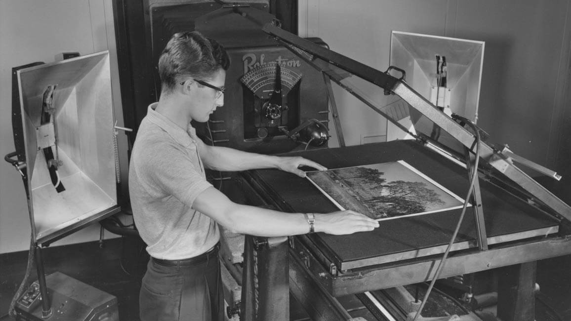 A student places a print on a piece of reproduction equipment.