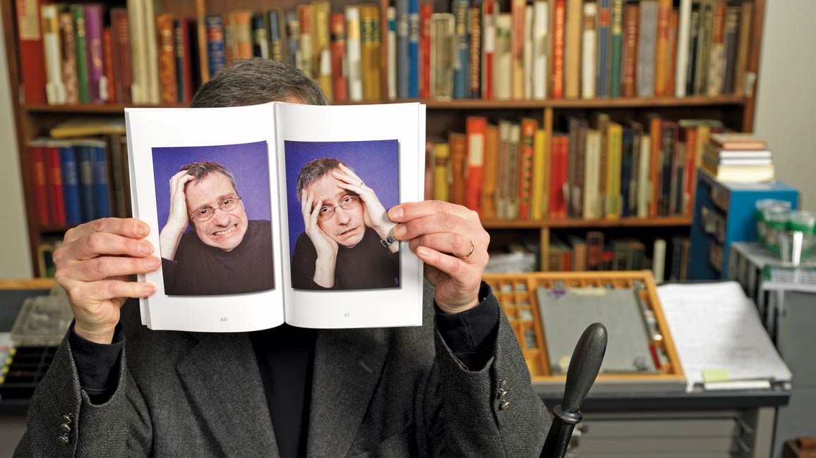 Guy holding a book with photos of himself over his face.