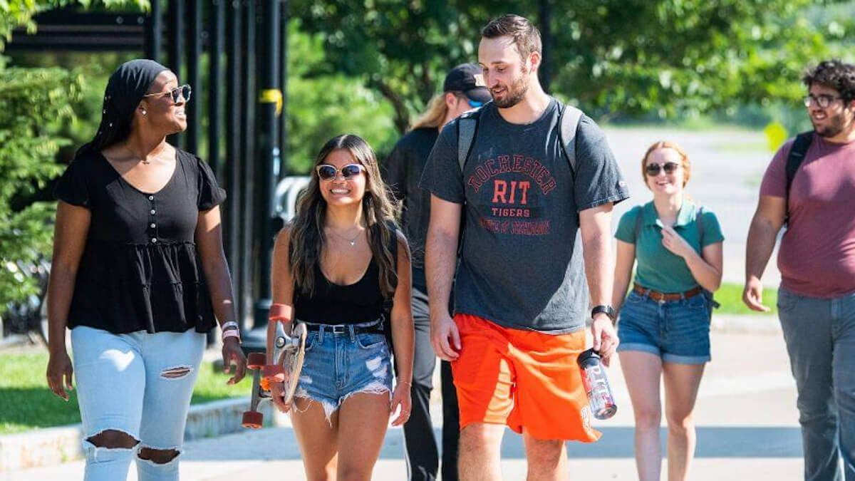 A group of students walking on one of the walkways of the R I T campus.