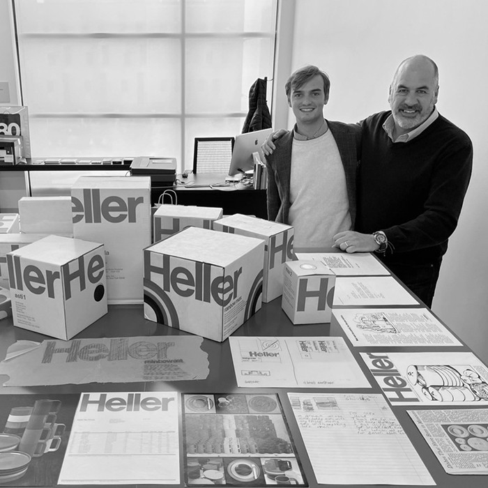Two people pose for a photo amidst artifacts from the vignelli center.