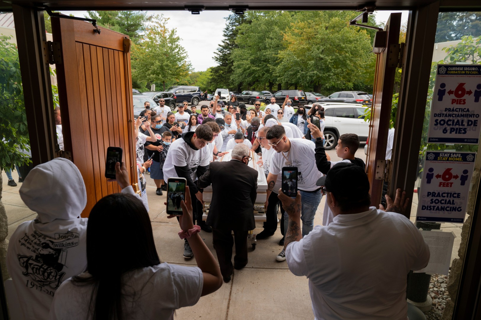 A group of people attend a funeral as attendees help move the casket.