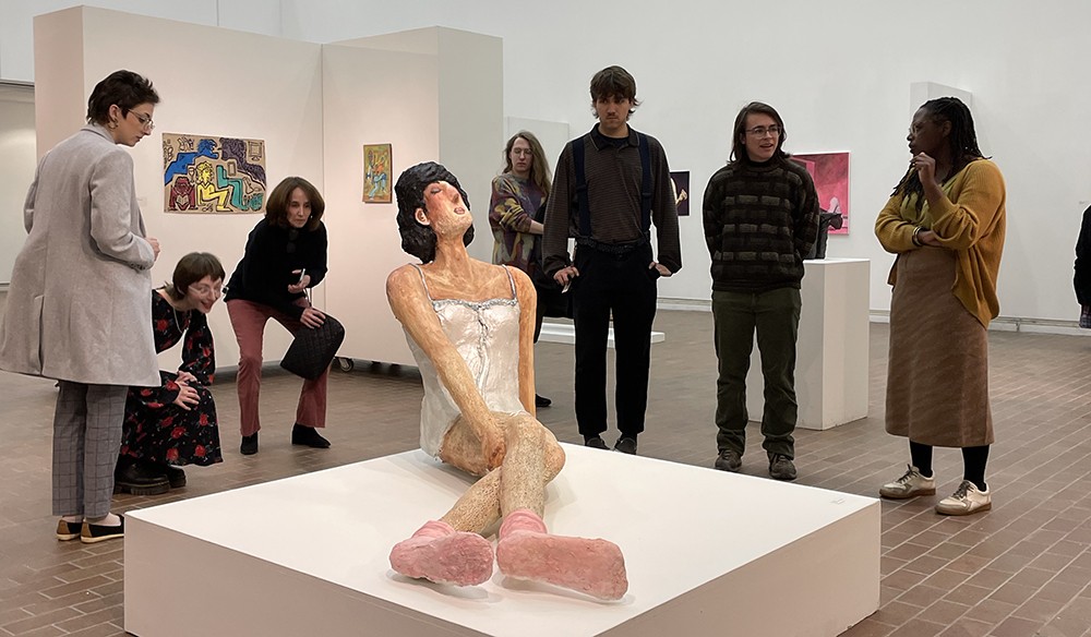 People in a gallery look at a sculpture.