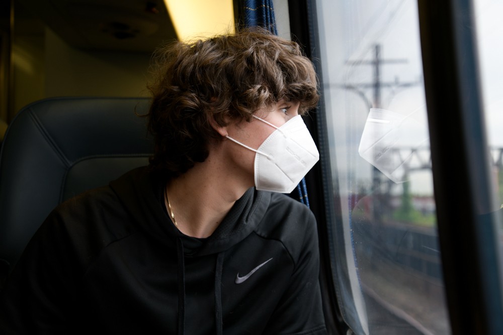 A boy wearing a mask on a train.