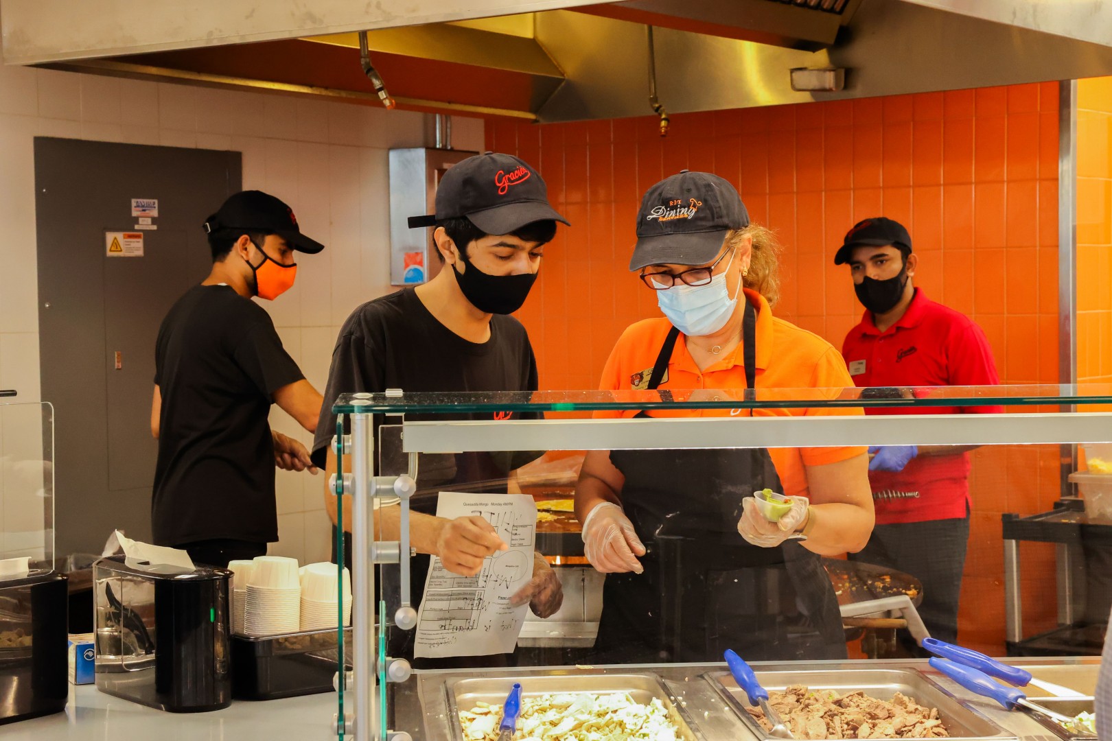 Two RIT Dining employees working behind a food station at Gracie's