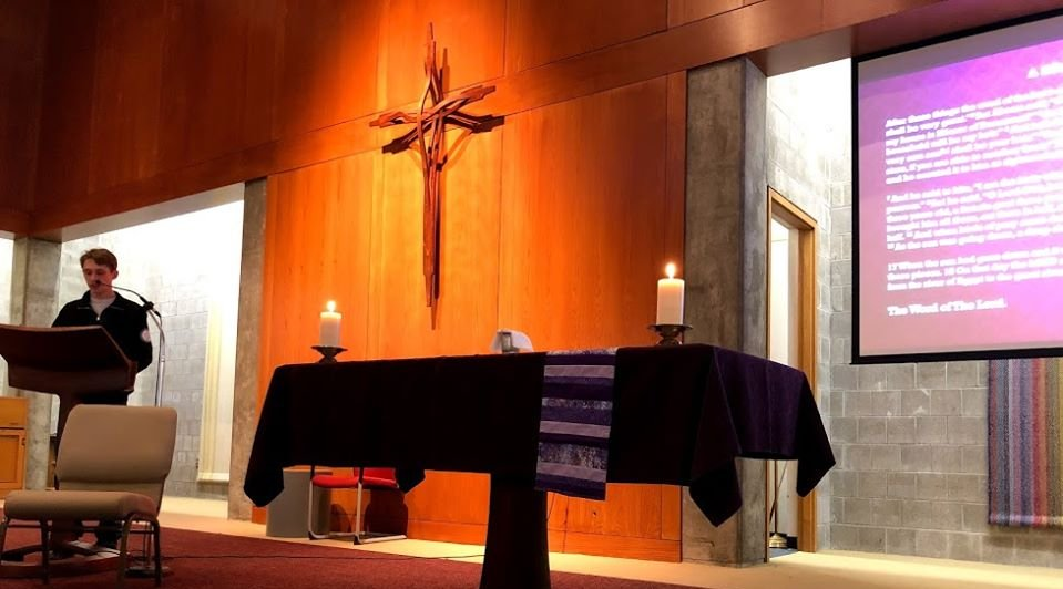 altar with candles, cross on wall, and student