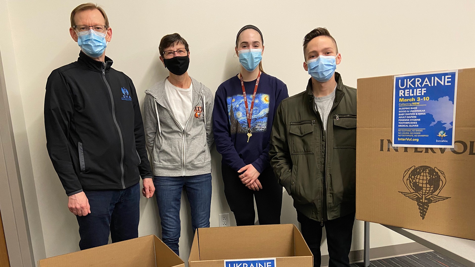four people standing next to cardboard collection boxes.