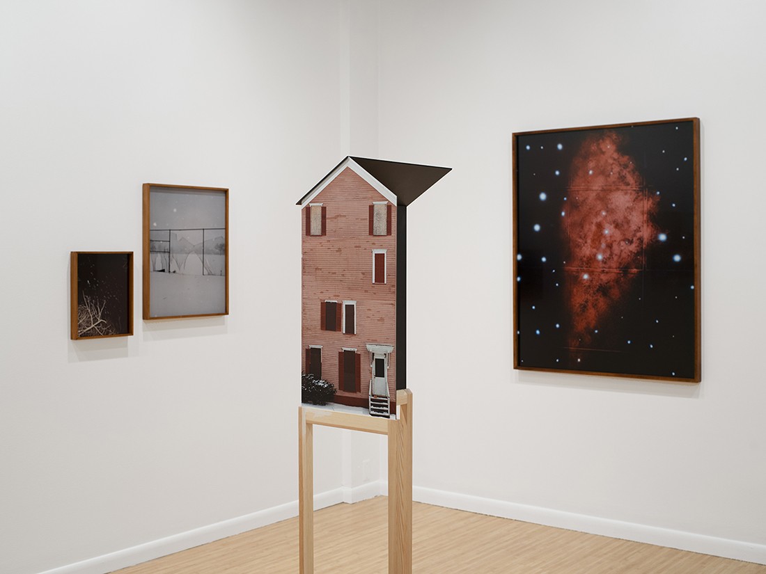An installation of a house next to photo prints.