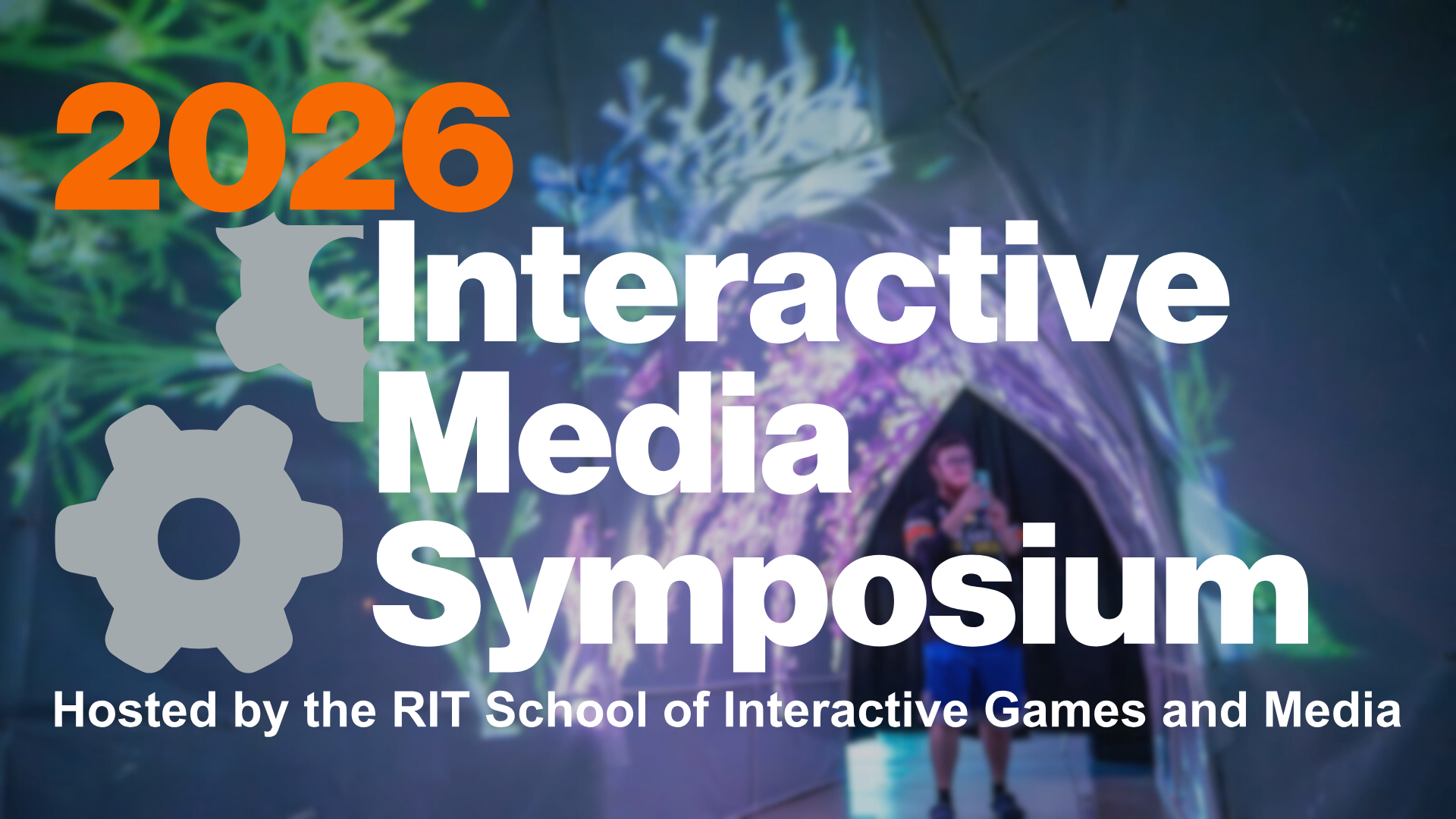 Image of person standing in a tunnel with projections along the wall with text: 2026 Interactive Media Symposium Hosted by RIT School of Interactive Games and Media