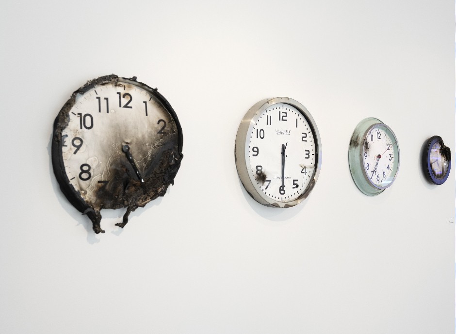 A display of burning clocks on a wall.