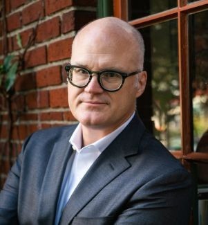 Image of the speaker Richard Ivan Jobs standing in front of a window with brick to the right of him
