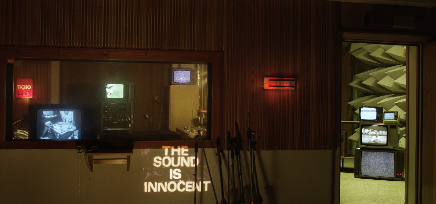A recording studio setting with projected text The Sound is Innocent.