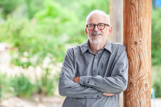 A headshot of John Melanson, crossing his arms. 