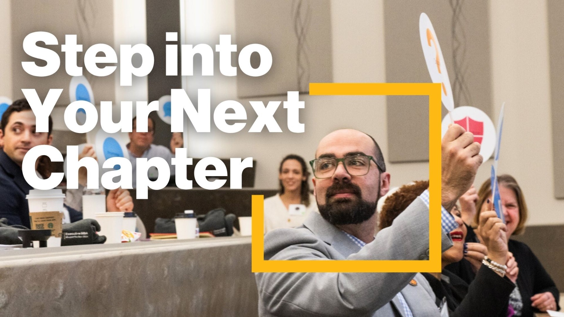 Image of a man in a classroom holding a informational sign with text on the graphic saying Step into Your Next Chapter