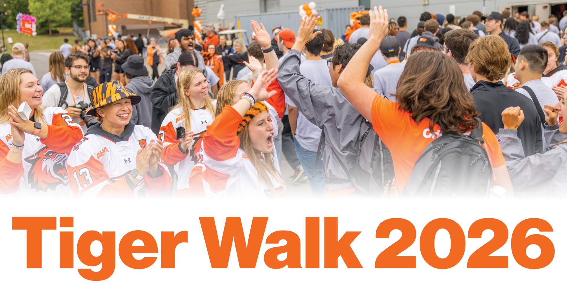 Students and campus community members line a pathway during Tiger Walk, cheering and high-fiving as new students arrive. The graphic features the text "Tiger Walk 2026."