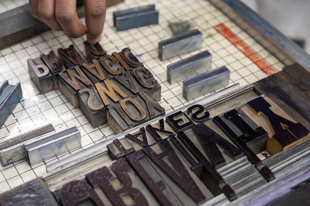 A detailed look at a student working with a letterpress.