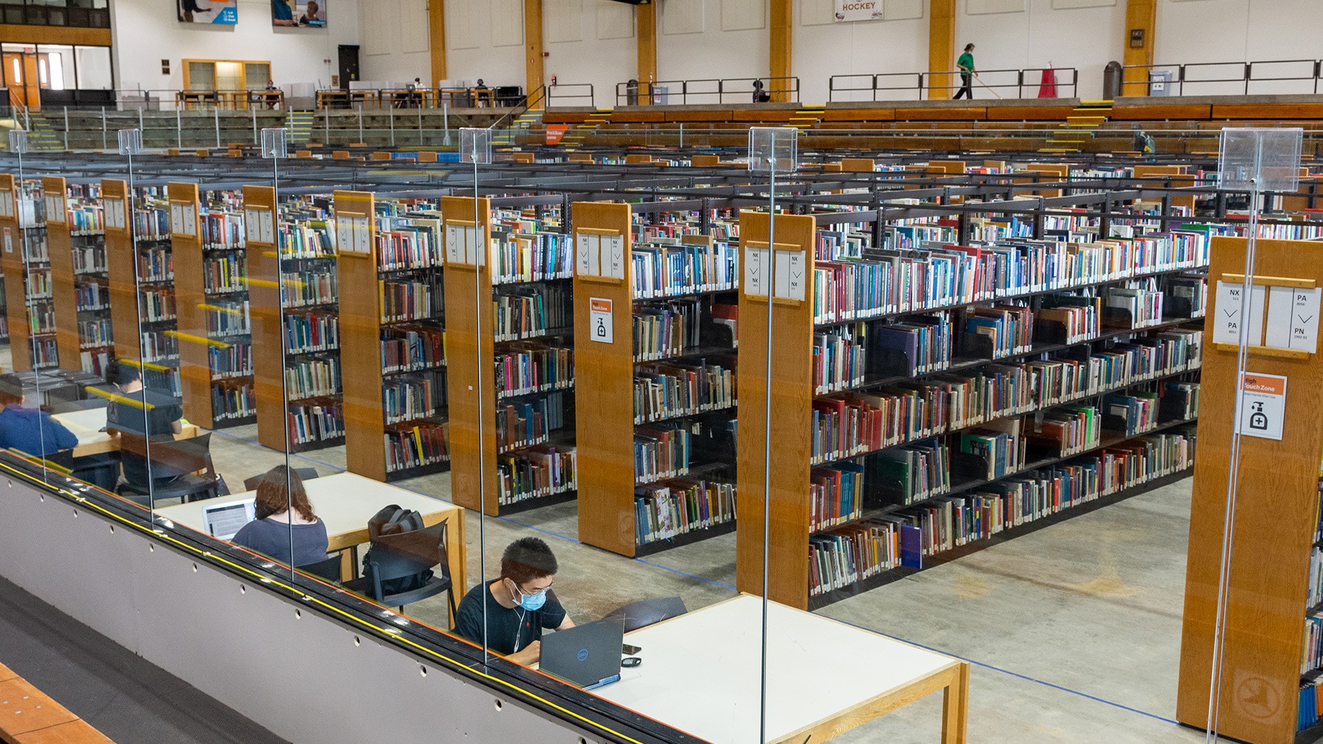 Students studying at tables in front of bookshelves full of library books in Wallace on Ice