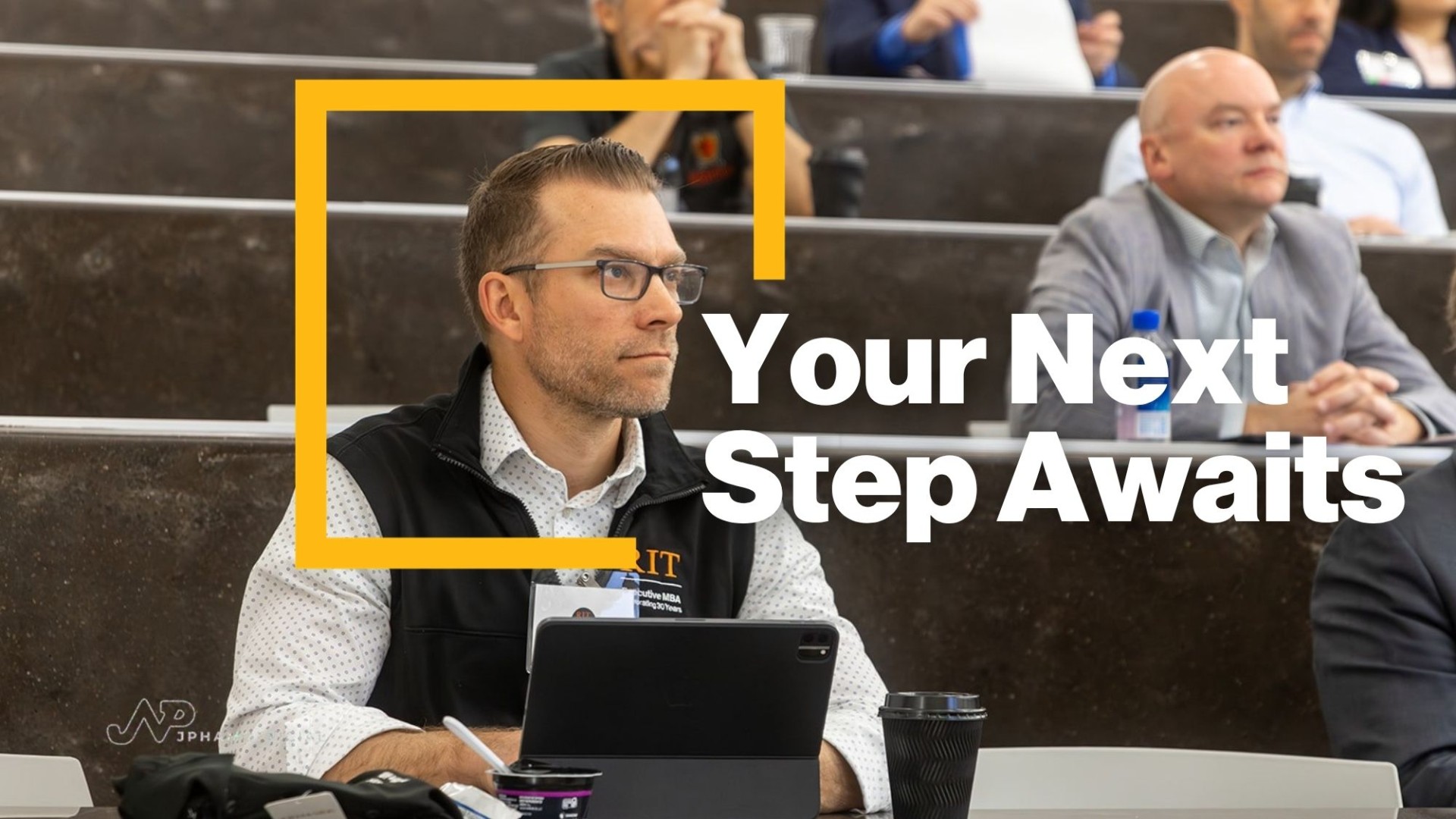 Image of a man in a classroom holding a informational sign with text on the graphic saying Your Next Step Awaits