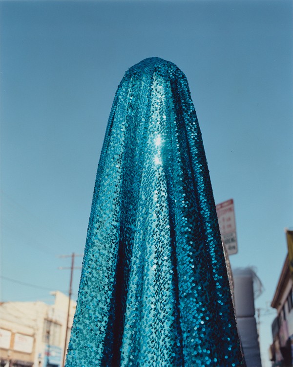 A pillar-shaped object stands tall in a city.