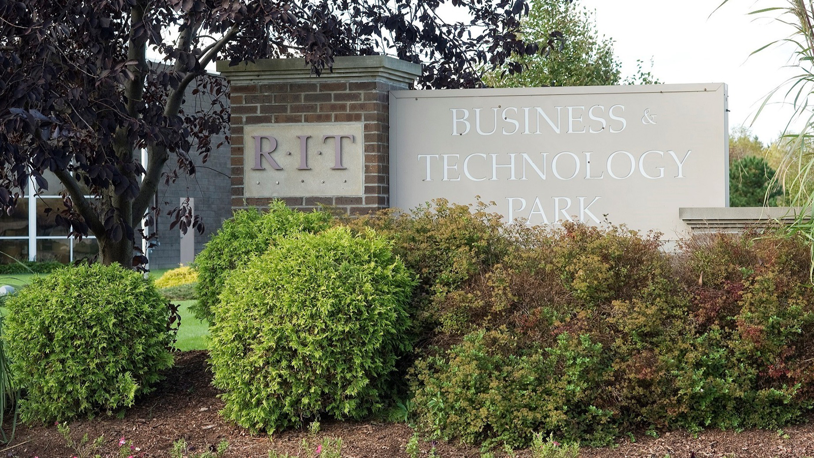 Outdoor sign for the R.I.T. Business & Technology Park surrounded by lush greenery.