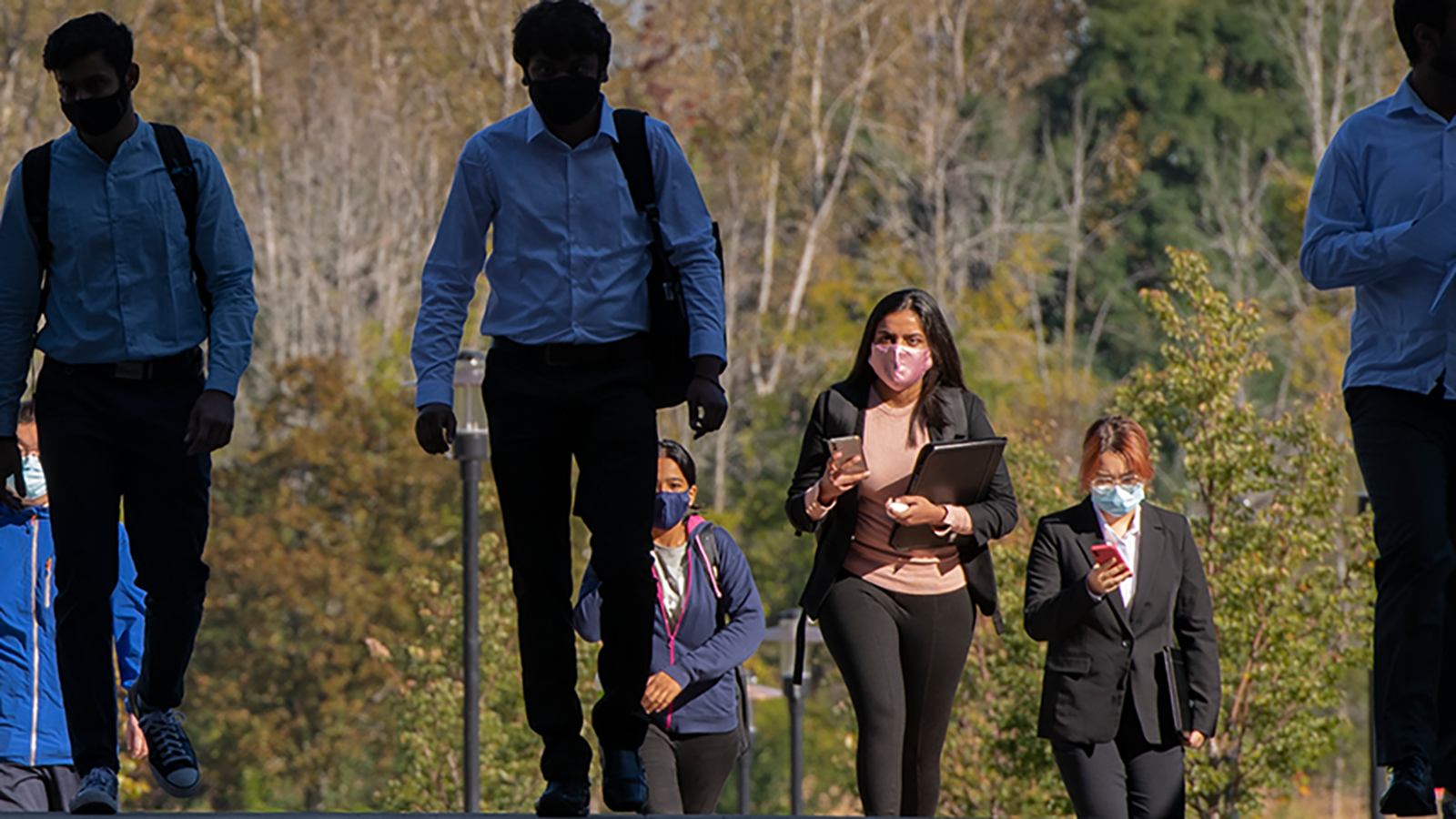 A group of professionally dressed individuals walking outdoors.