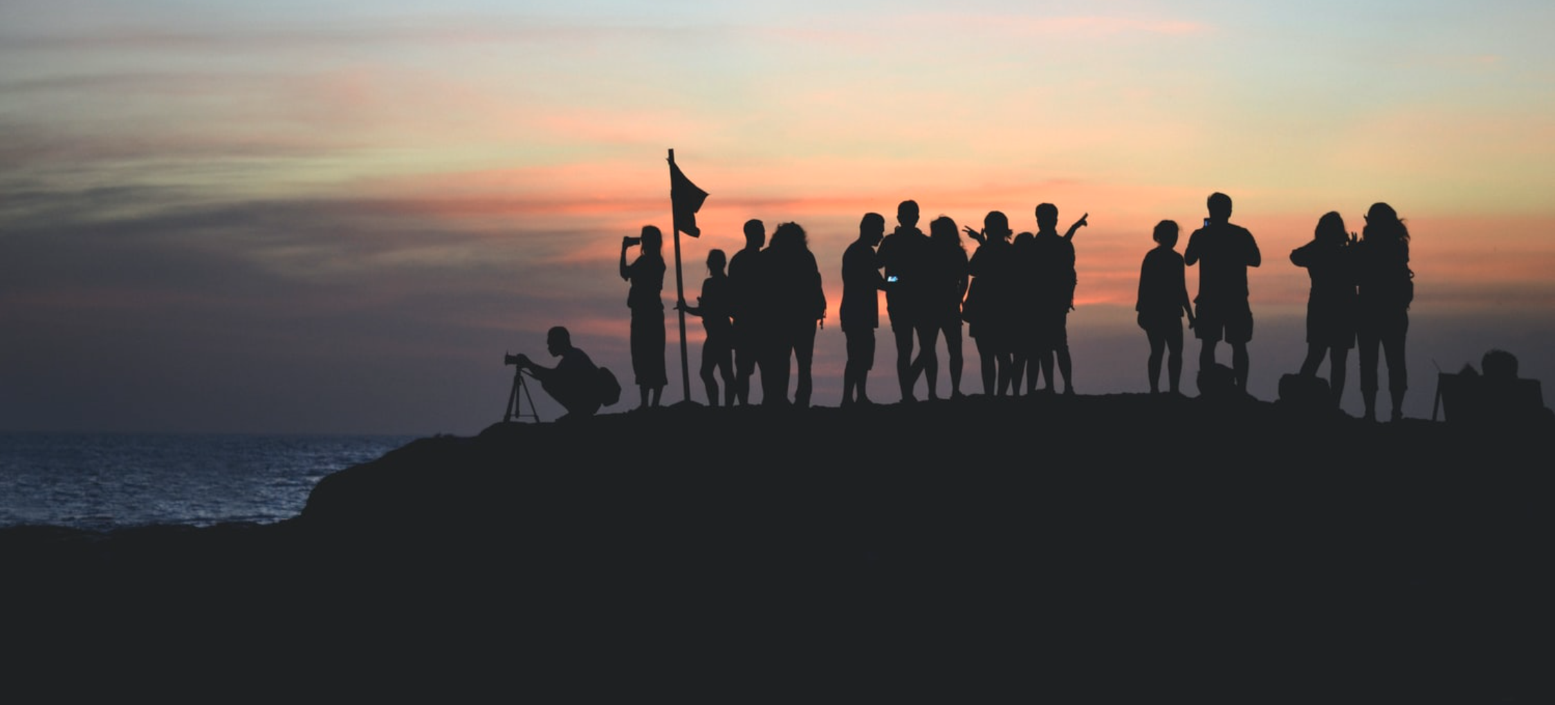 Silhouette of friends watching the sunset from a mountaintop