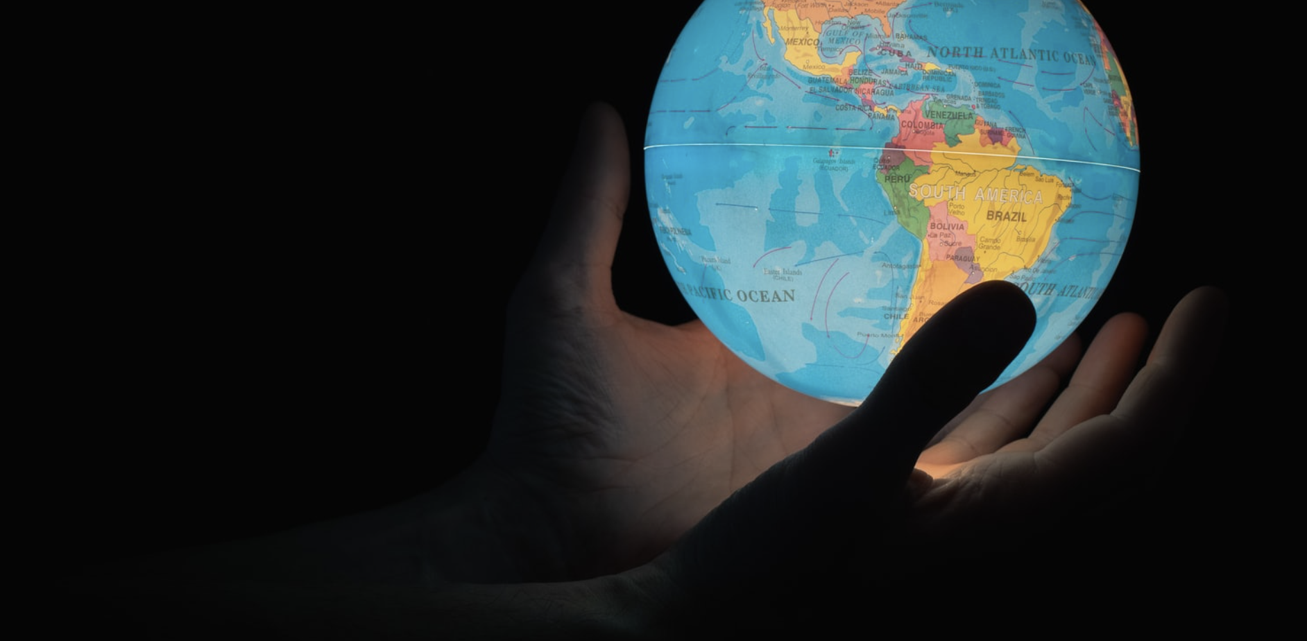 Silhouette of hands holding a glowing globe