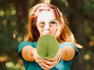 A girl holding a leaf with a focus around the leaf