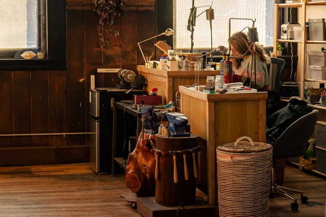 person working in a studio surrounded by metalworking tools and supplies.