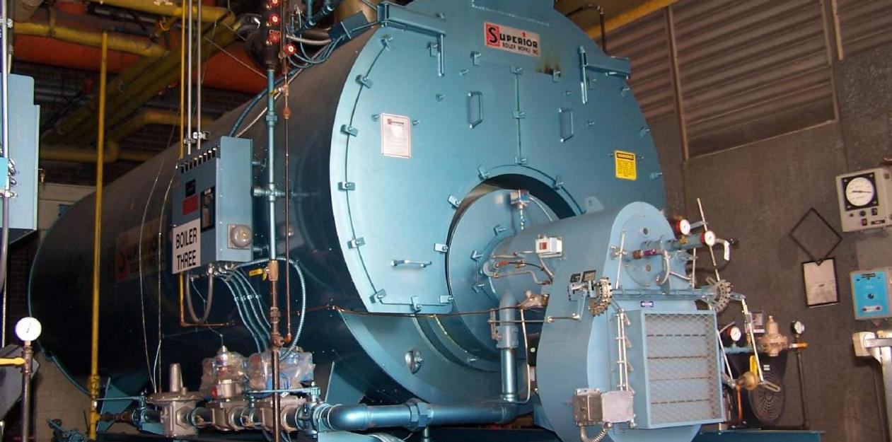 A large blue boiler in a room with concrete walls