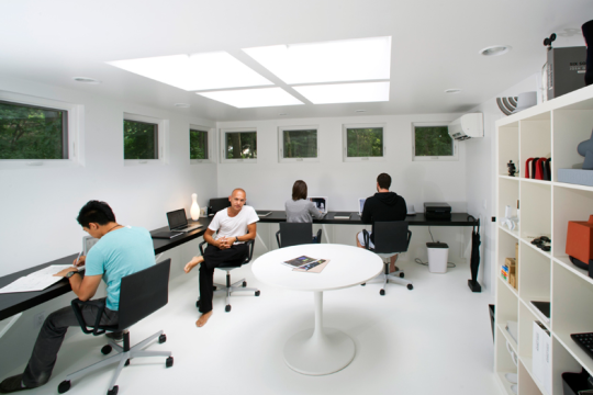 Josh Owens sits in his white, clean, and sleak design studio amoung other designers.