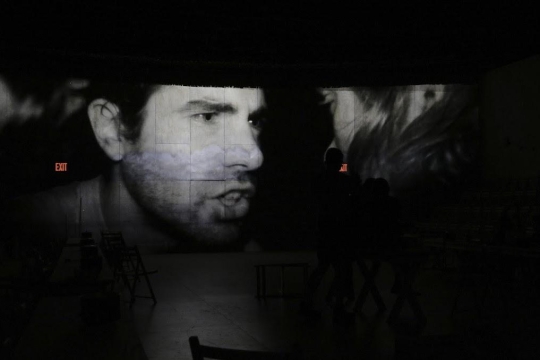 Image of man's face projected on wall in black and white.