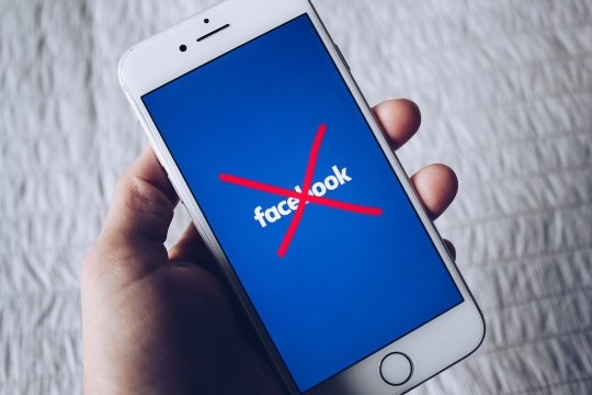 Facebook app on a smartphone with a red X over it