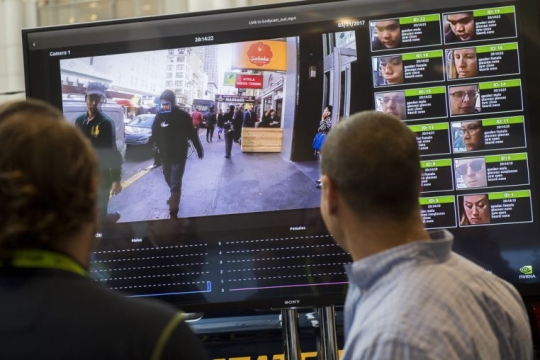 People look at monitor with display of faces.