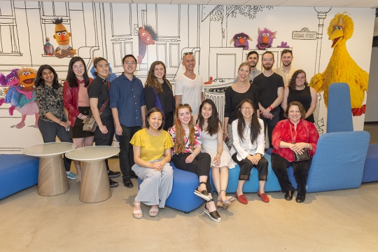 a group of people in front of a Sesame Street mural