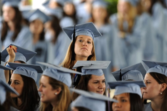 Crowd of college grads with one student poking head above crowd.