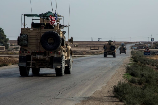 U.S. military trucks drive down road.