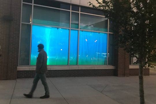 Man walks by art exhibit displayed in window.