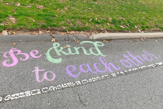 sidewalk chalk art that says Be kind to each other.