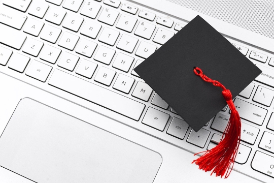 small graduation cap sitting on computer keyboard.