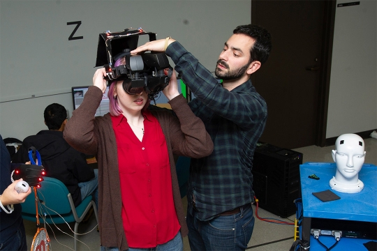 professor helping student put on virtual reality headset.
