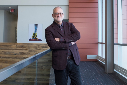 professor standing in hallway with arms crossed.