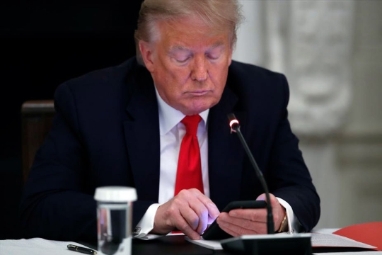 President Trump looking at a smartphone.