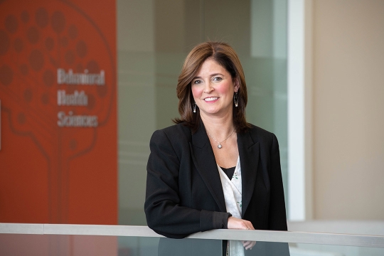 researcher standing in atrium of behavioral health sciences building.