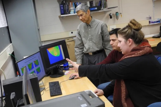 professor looking at computers with two students.